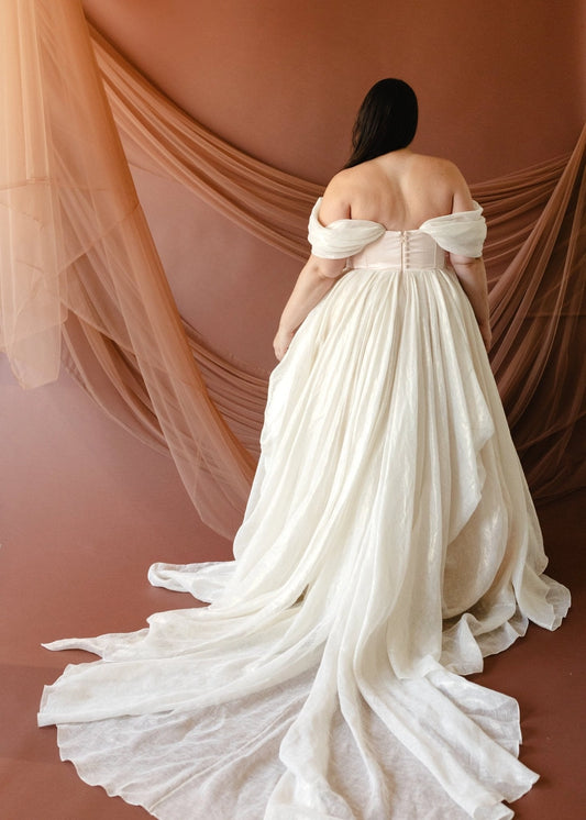 Ivory plus size off-shoulder wedding dress with button-detail corset back, gathered A-line skirt and romantic flowing train