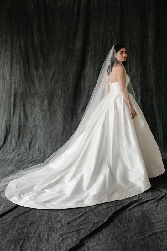 Ivory plus size satin wedding dress with strapless fitted back, voluminous ball gown skirt and sweeping bridal train back view