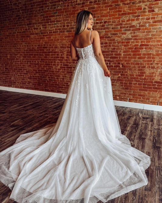 Ivory plus size wedding dress with lace-up corset back, floral lace appliques and flowing chapel-style tulle train