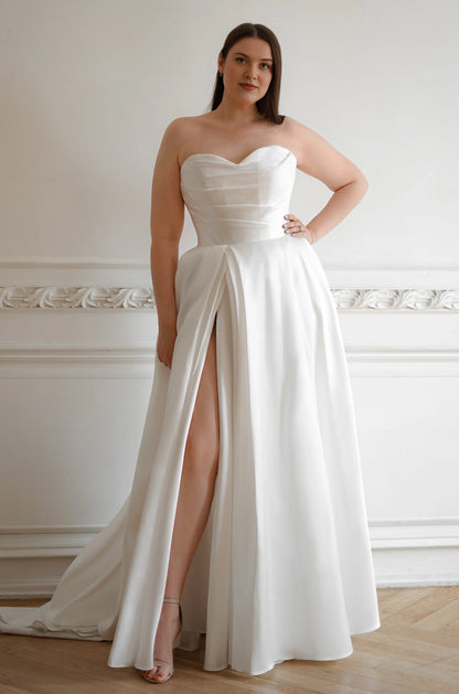 White plus size A-line wedding dress with strapless sweetheart neckline, ruched satin-look bodice, thigh-high slit and flowing train